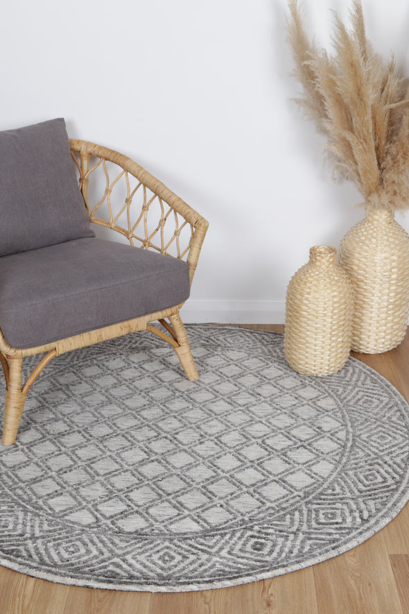 Alayah Diamond Trellis grey & taupe circle Rug with grey chair on light flooring