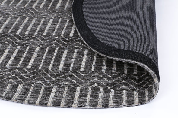 Alayah Geometric grey & ash circle Rug folded over to show the dark cotton backing