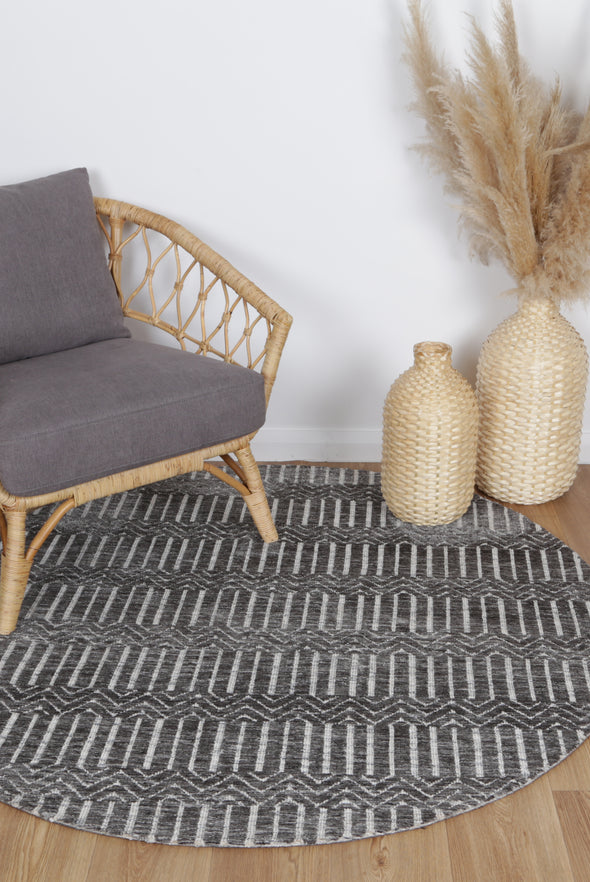 Alayah Geometric grey & ash circle Rug in sitting room on light flooring with dried flower, woven baskets and a grey chair