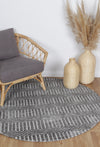Alayah Geometric charcoal circle Rug wooden flooring with grey chair and wicker baskets