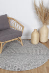 Alayah Tessellations silver & taupe circle Rug with grey chair on natural flooring and wicker chair and accessories