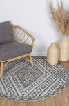 Alayah Zalij grey & taupe circle Rug in sitting room with light flooring, a grey chair and wicker accessories