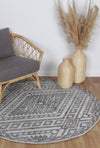 Alayah Zalij charcoal circle Rug in living room with grey chair and raatan accessories on light flooring