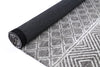 Alayah Diamond Trellis Silver Rug rolled with dark cotton back on white flooring