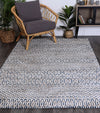 Alayah Camphils Blue Rug in living room on dark flooring with wicker and grey chair