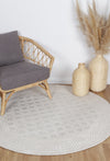 Alayah Diamond Trellis ivory circle Rug in living room with a grey whicker chair and light flooring