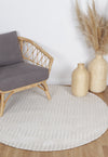 Alayah Geometric Ivory circle Rug in sitting room with natural flooring and a grey armchair