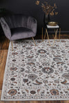 Almada Charcoal Floral Rug in lounge room with grey velvet chair on natural wood floors, with gold and brass accessories